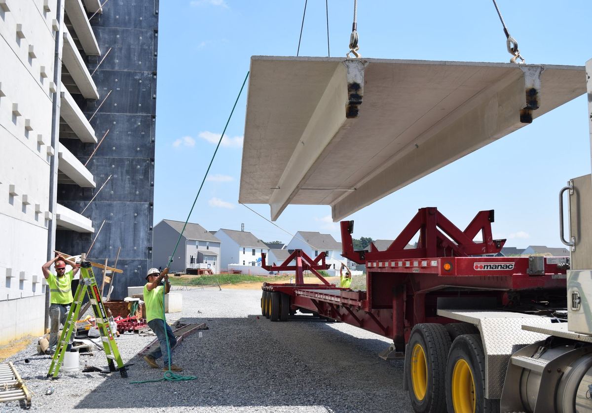 Ironworkers guiding a precast double tee off the trailer at a parking structure