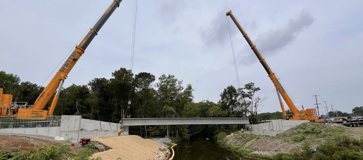 Twin cranes setting a precast concrete bridge beam