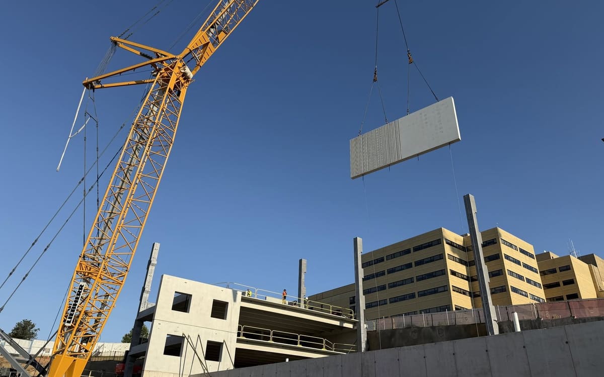 Crane flying a precast double tee into a parking structure