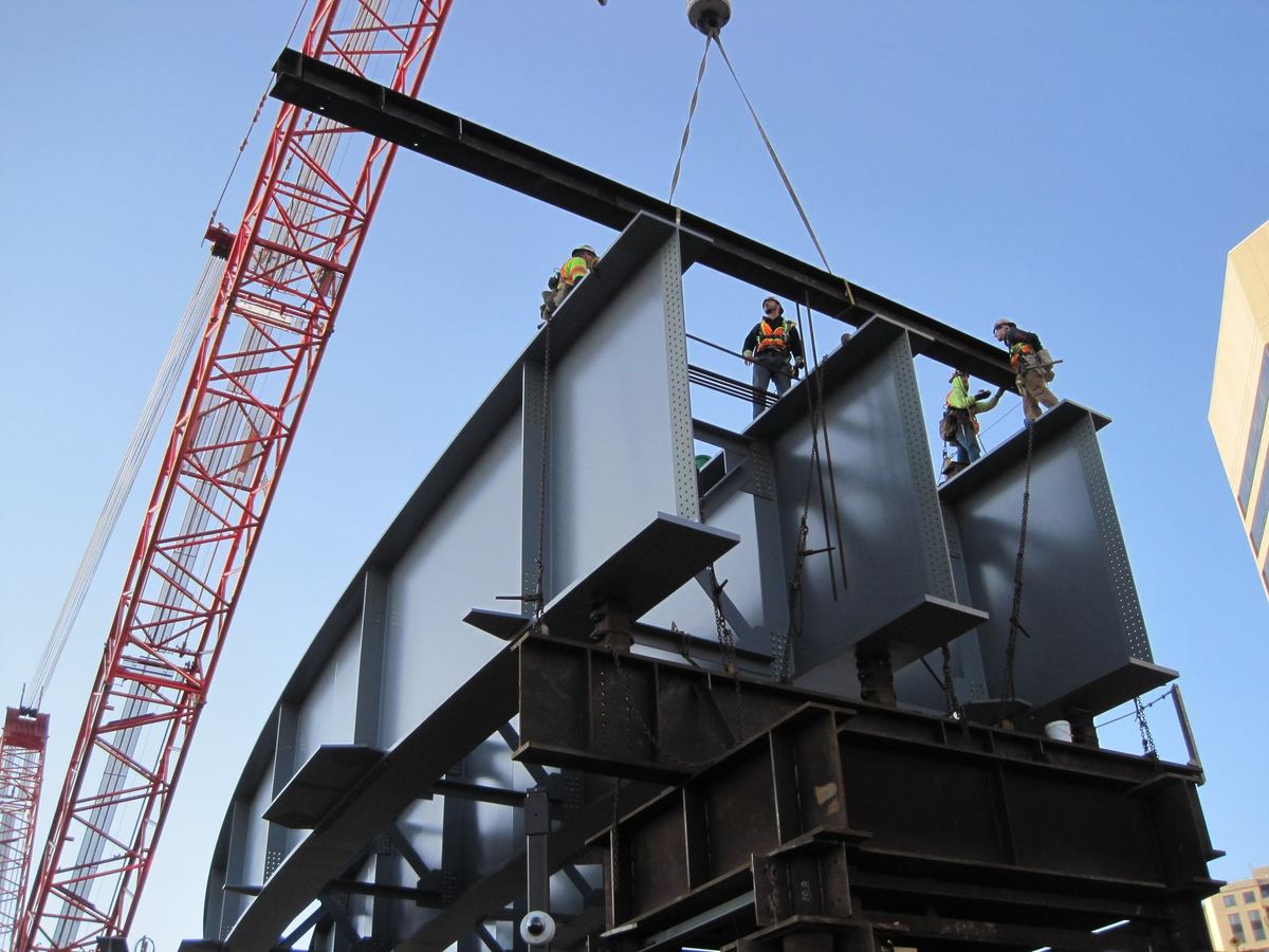 Ironworkers guiding a steel plate girder assembly into place