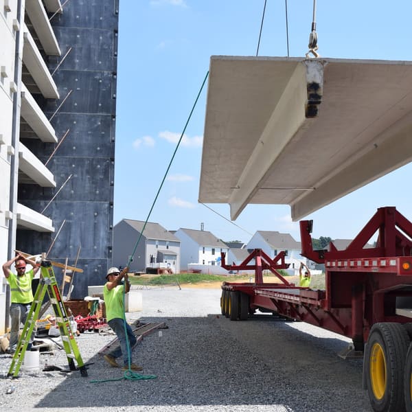 Crane lifting a precast double tee off the trailer at a parking structure