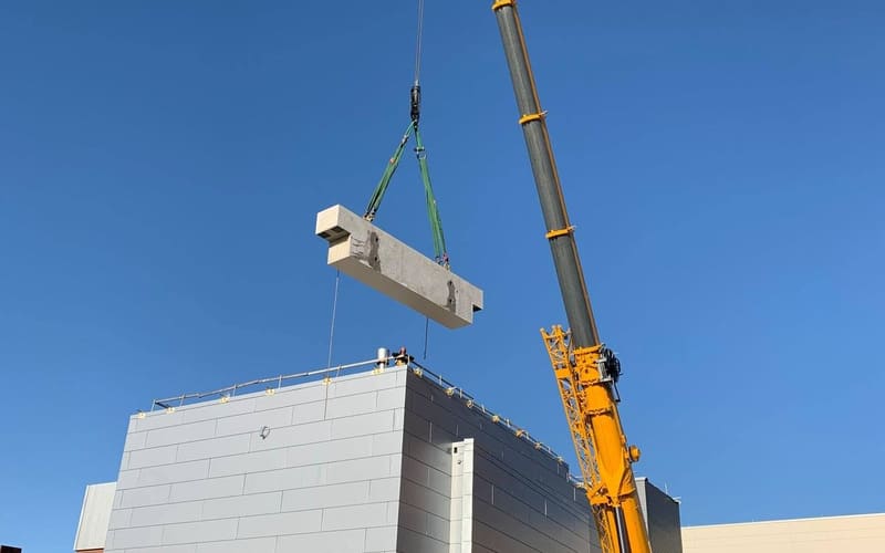 Precast concrete beam on the crane hook above a building under erection