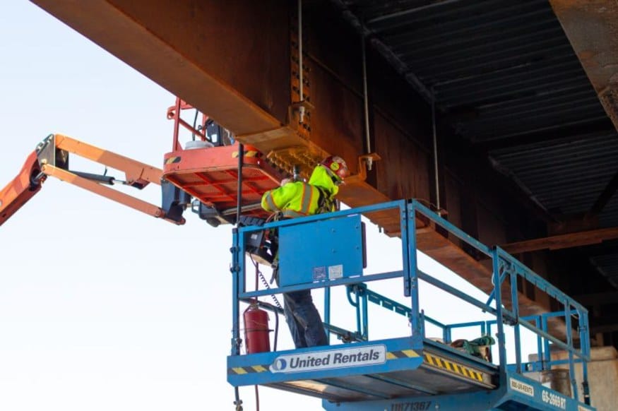 HSE ironworker on a lift at the underside of a damaged steel girder in Goshen, New York